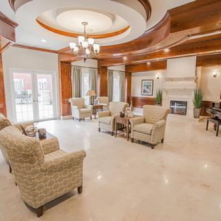 A spacious and elegantly designed living room with a cozy seating area, fireplace, and chandelier.
