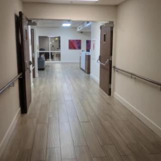 A hospital hallway with open doors and handrails.
