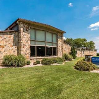 A beautifully designed stone building surrounded by well-maintained grass and a clear blue sky.