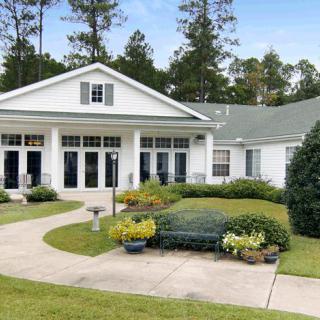 A charming house with a well-maintained garden and surrounding trees.