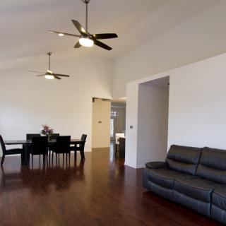 A spacious living and dining area with modern furniture and ceiling fans.