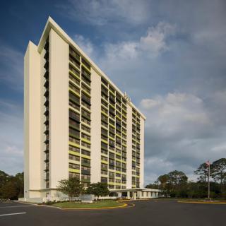 A modern high-rise residential building under a partly cloudy sky.