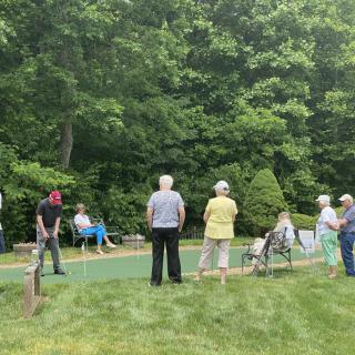A group of seniors enjoying a day of minigolf surrounded by greenery.