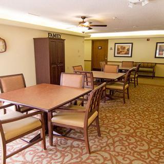 A well-lit indoor dining area with tables and chairs arranged on a carpeted floor.