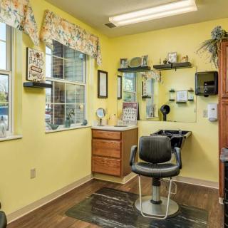 A cozy hair salon with yellow walls and a comfortable styling chair by the window.