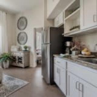 A modern kitchen interior featuring white cabinets, a stainless steel refrigerator, and tasteful decor.