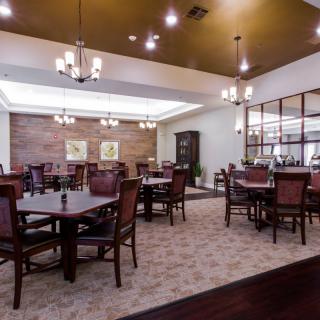 A spacious and elegantly designed dining area with multiple tables and chairs, featuring ambient lighting and tasteful decor.
