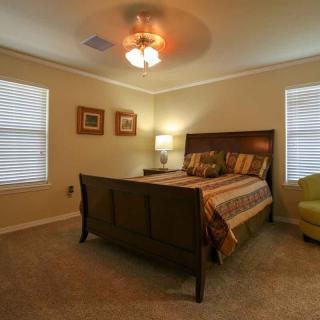 A cozy bedroom with a wooden bed, soft lighting, and comfortable seating.