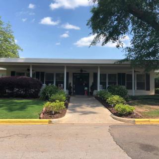A view of a building entrance with landscaping and a sunny sky.