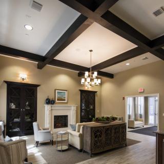 A modern living room with a cozy seating area, featuring a central fireplace and elegant chandelier.
