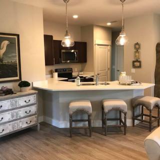 A modern kitchen with a white countertop, bar stools, and pendant lighting.