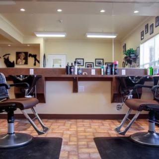 The interior of a barbershop showing styling chairs, mirrors, and hair products neatly arranged.