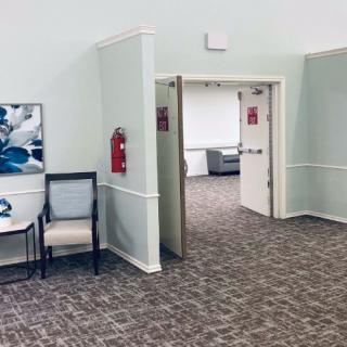 An open doorway leading into a room, with chairs and artwork in a hallway.