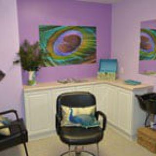 A cozy salon space with purple walls, featuring a comfortable chair and vibrant artwork.