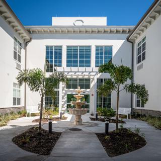 A modern building courtyard featuring a central fountain and palm trees.