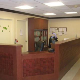 A reception area with a wooden desk and office decor.