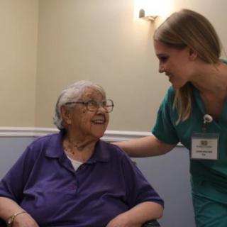 A nurse providing support and care to an elderly woman in a healthcare setting.