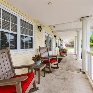 A spacious porch featuring wooden chairs with red cushions and a view of the yard.