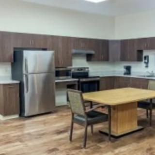 A modern kitchen with wooden cabinetry, stainless steel appliances, and a dining table.