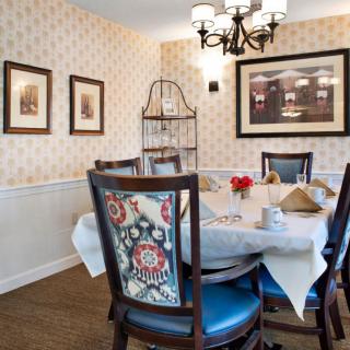 A cozy dining room featuring a round table with stylish chairs, adorned with a chandelier and decorative wall art.