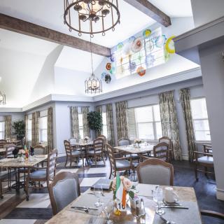 A bright and elegant dining room with wooden tables and chandeliers.