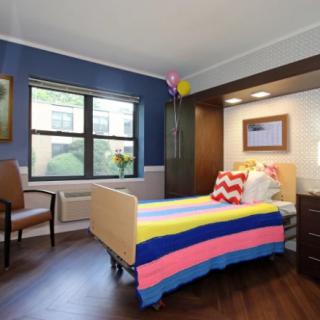 A brightly decorated bedroom with colorful bedding, a large window, and balloons.