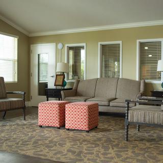 A cozy living room with a sofa, chairs, and colorful ottomans.