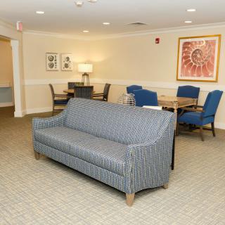 A cozy living room area featuring a striped sofa, blue chairs, and a decorative artwork on the wall.