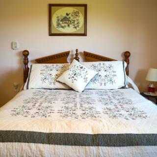 A beautifully arranged bedroom featuring a cozy bed with decorative pillows and a charming piece of wall art.
