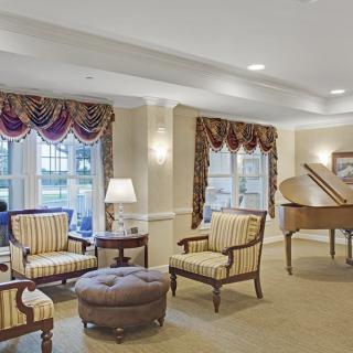 A well-furnished living room featuring elegant seating and a grand piano.