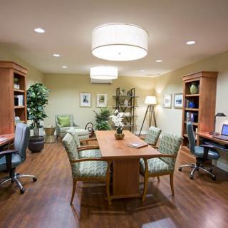 A well-organized conference room with a central wooden table, chairs, and workstations on either side.