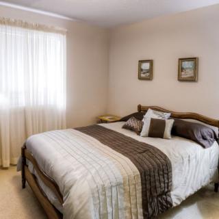 A cozy bedroom with a neatly made bed, decorative pillows, and soft lighting.