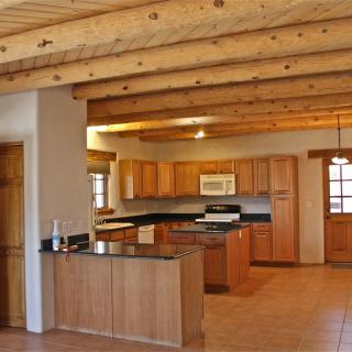A spacious kitchen with wooden ceiling beams and warm-toned cabinets.