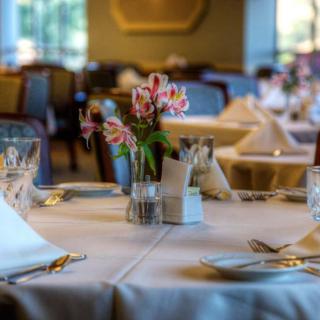 An elegantly set dining table with flowers, glasses, and napkins in a restaurant.