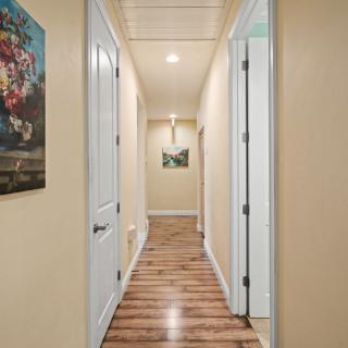 A well-lit hallway with wooden floors and paintings on the walls.