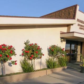 A building entrance surrounded by rose bushes and other plants.