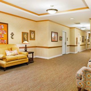 A warmly decorated hallway with comfortable seating and framed artwork on the walls.