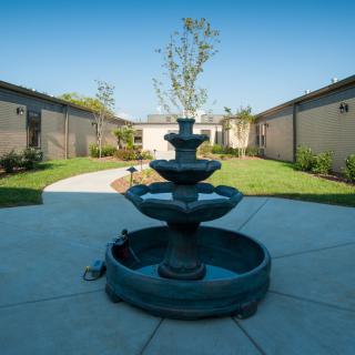 A serene courtyard featuring a tiered fountain at its center, surrounded by well-maintained gardens and pathways.