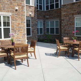 An outdoor patio with tables and chairs set against a brick building.