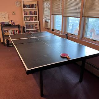 A spacious ping pong table set up indoors, ready for a game.
