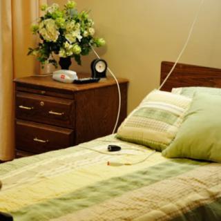 A cozy bedroom with a neatly made bed, a nightstand, and a floral arrangement.
