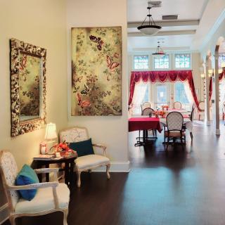 Elegant interior with a hallway leading to a dining area, featuring classic chairs and vibrant artwork.