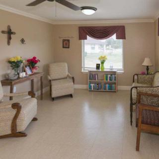 A cozy living room with plush chairs, a window with drapes, and a small bookshelf.