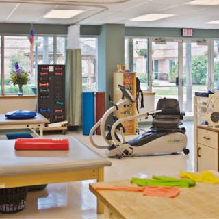 A bright and spacious physical therapy clinic equipped with various exercise tools and therapy tables.