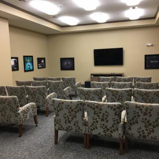 A cozy home theater room with patterned seating and a wall-mounted television.