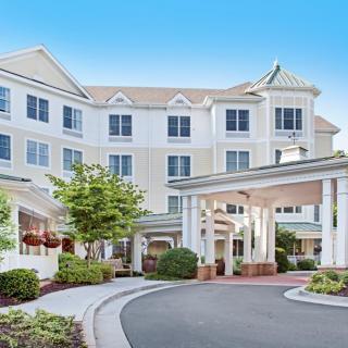 A spacious hotel entrance with a circular driveway and well-maintained landscaping.