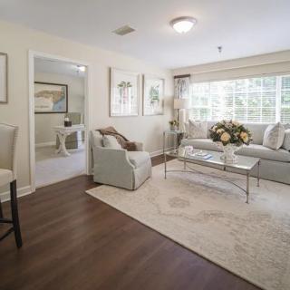 A cozy and elegantly decorated living room with a sofa, armchair, coffee table, and large window.