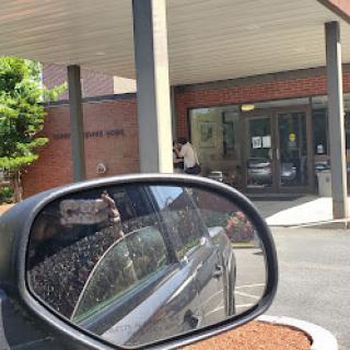 A view from a car's side mirror showing the entrance of a building.
