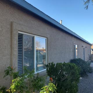A side view of a residential building featuring windows and surrounding greenery.