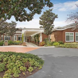 A building with a sheltered entrance, surrounded by trees and landscaped gardens.